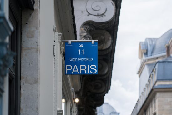 Blue sign mockup hanging on building exterior with Paris text, clear sky, urban setting for designers.